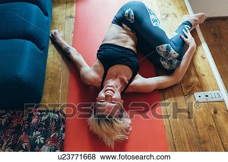 Stock Photo - Woman practising yoga at home. Fotosearch