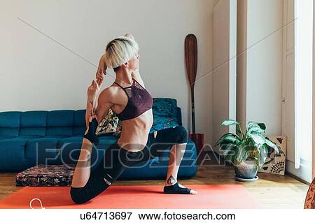 Stock Photo - Woman practising yoga at home. Fotosearch