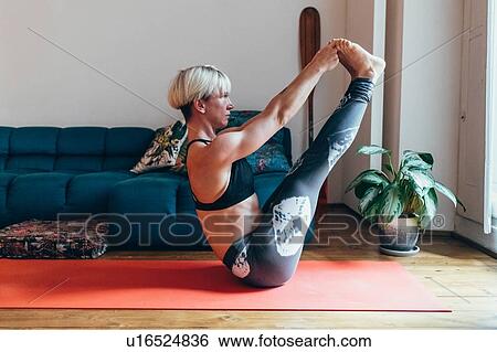 Stock Photograph - Woman practising yoga at home. Fotosearch