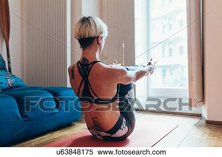 Stock Photography - Woman practising yoga at home. Fotosearch