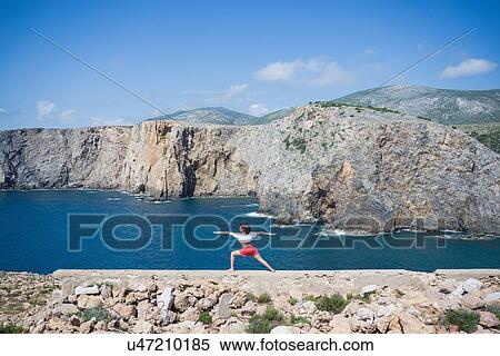 Stock Photography - Woman practising yoga on hilltop, Iglesias, Sardinia, Italy. Fotosearch
