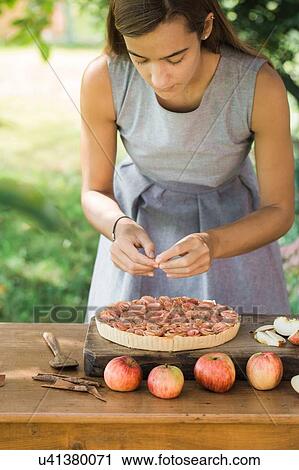 Stock Image - Woman preparing apple pie on table. Fotosearch