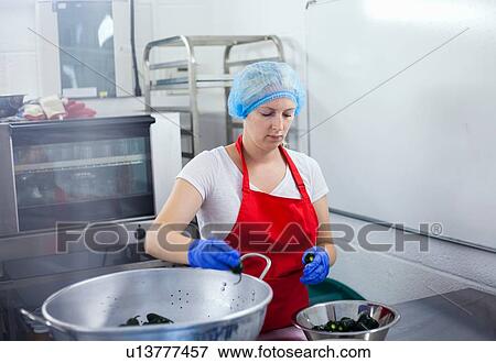 Stock Photo - Woman preparing chillies to make jam in industrial kitchen. Fotosearch
