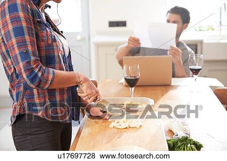 Woman preparing vegetables at kitchen table, boyfriend reading paperwork View Large Photo Image Stock Photo - Woman preparing vegetables at kitchen table, boyfriend reading paperwork. Fotosearch