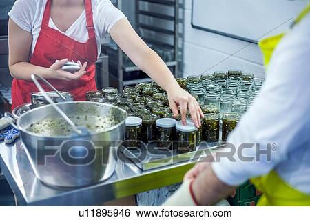 Woman putting lids on jars of jam in industrial kitchen, mid section View Large Photo Image Stock Photograph - Woman putting lids on jars of jam in industrial kitchen, mid section. Fotosearch
