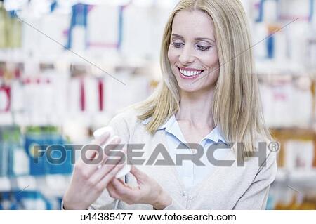 Woman reading label on pill bottle in pharmacy. View Large Photo Image Stock Photo - Woman reading label on pill bottle in pharmacy.. Fotosearch