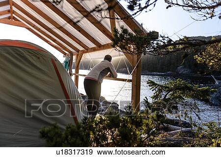 Stock Photo - Woman relaxing by lakeside, Johnstone Strait, Telegraph Cove, Canada. Fotosearch