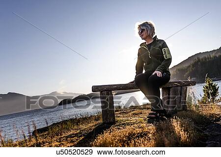 Stock Photo - Woman relaxing by lakeside, Johnstone Strait, Telegraph Cove, Canada. Fotosearch
