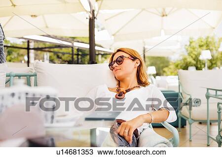 Stock Image - Woman relaxing on terrace. Fotosearch