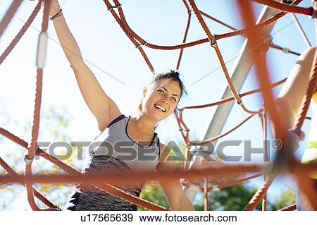 Stock Photo - Woman rope climbing in park. Fotosearch