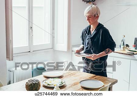 Woman setting table in kitchen View Large Photo Image Stock Photo - Woman setting table in kitchen. Fotosearch