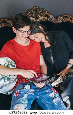 Woman sitting on antique sofa with son View Large Photo Image Stock Photo - Woman sitting on antique sofa with son. Fotosearch
