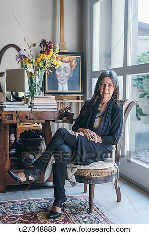 Stock Photo - Woman sitting on armchair by window. Fotosearch