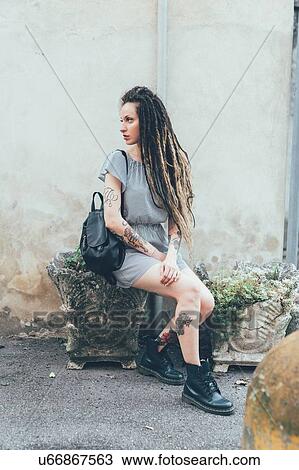 Stock Image - Woman sitting on stone stool. Fotosearch