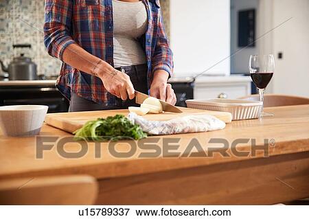 Woman slicing onion at kitchen table, mid section View Large Photo Image Stock Photo - Woman slicing onion at kitchen table, mid section. Fotosearch