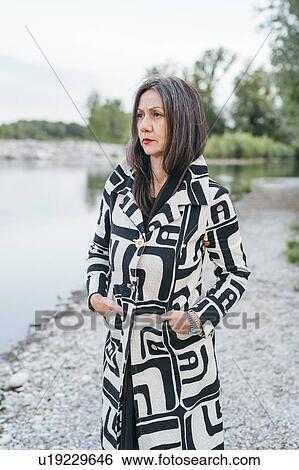 Stock Photograph - Woman standing by lake. Fotosearch