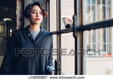 Stock Photo - Woman standing by window. Fotosearch