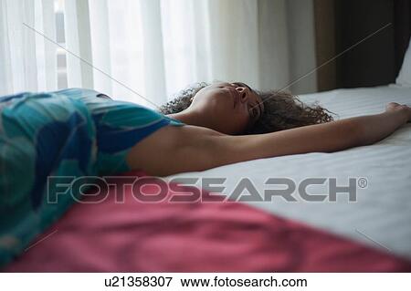 Stock Photo - Woman stretched out on bed. Fotosearch