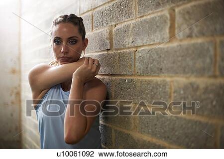 Stock Image - Woman stretching arm in gym. Fotosearch