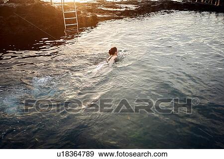 Stock Photo - Woman swimming in coastal pool at sunset, Las Palmas, Gran Canaria, Canary Islands, Spain. Fotosearch