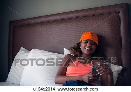 Woman texting on bed View Large Photo Image Picture - Woman texting on bed. Fotosearch