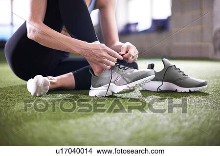 Woman tying shoelace in gym View Large Photo Image Picture - Woman tying shoelace in gym. Fotosearch
