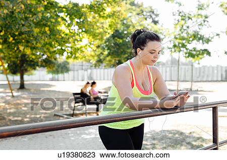 Woman using cellphone in park, friends taking break in background View Large Photo Image Stock Image - Woman using cellphone in park, friends taking break in background. Fotosearch