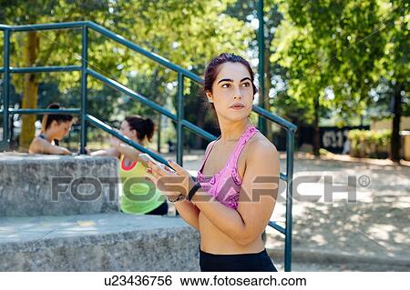 Woman using cellphone in park, friends taking break in background View Large Photo Image Stock Photograph - Woman using cellphone in park, friends taking break in background. Fotosearch