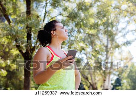 Woman using cellphone in park View Large Photo Image Stock Photo - Woman using cellphone in park. Fotosearch