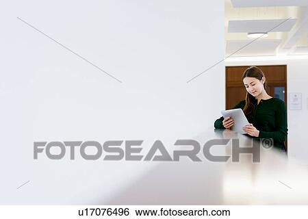 Stock Photograph - Woman using digital tablet on low wall. Fotosearch