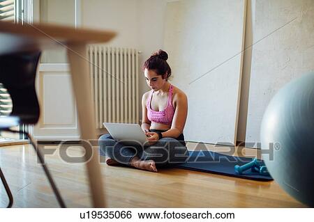 Stock Photograph - Woman using laptop in exercise clothes. Fotosearch