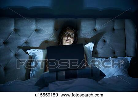 Stock Photo - Woman using laptop on bed. Fotosearch