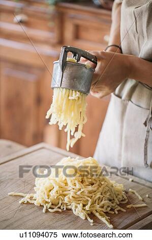 Stock Photography - Woman using potato ricer to prepare gnocchi. Fotosearch