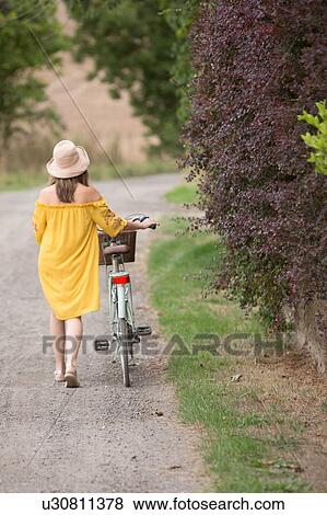 Woman walking bicycle in countryside View Large Photo Image Stock Photo - Woman walking bicycle in countryside. Fotosearch