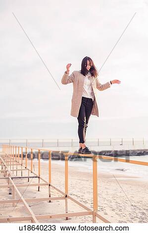 Woman walking on handrail at beach View Large Photo Image Stock Image - Woman walking on handrail at beach. Fotosearch
