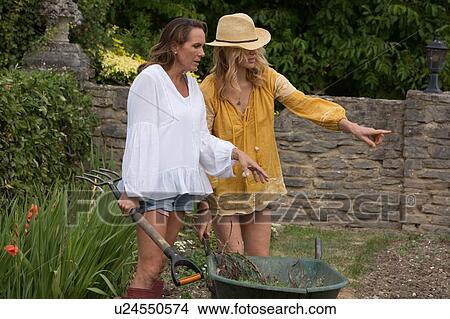 Picture - Women using wheelbarrow in garden. Fotosearch