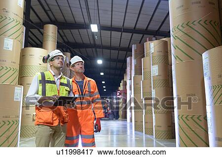Workers using digital tablet in paper storage area of port View Large Photo Image Stock Photo - Workers using digital tablet in paper storage area of port. Fotosearch