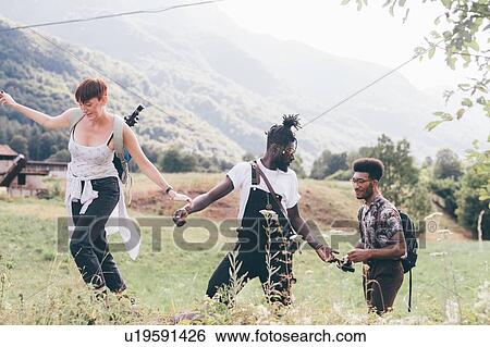 Stock Photograph - Young adult hikers hiking in field landscape, Primaluna, Trentino-Alto Adige, Italy. Fotosearch