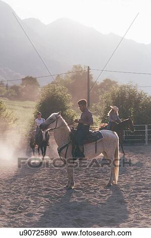 Stock Image - Young adults horse riding in rural equestrian arena, Primaluna, Trentino-Alto Adige, Italy. Fotosearch