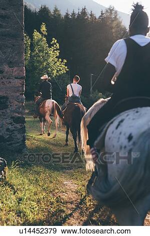 Stock Photo - Young adults riding on rural track, rear view, Primaluna, Trentino-Alto Adige, Italy. Fotosearch