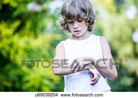 Picture - Young boy scratching arm.. Fotosearch