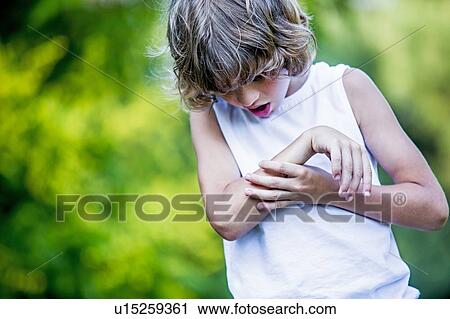 Stock Image - Young boy scratching arm.. Fotosearch