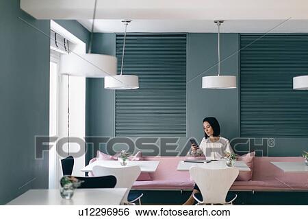 Young businesswoman at hotel table looking at smartphone View Large Photo Image Stock Photograph - Young businesswoman at hotel table looking at smartphone. Fotosearch