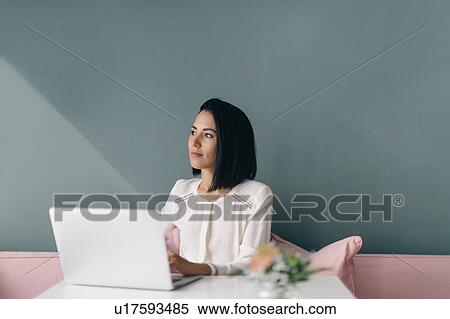 Stock Photography - Young businesswoman at hotel table daydreaming. Fotosearch