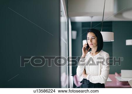 Picture - Young businesswoman in hotel making smartphone call. Fotosearch