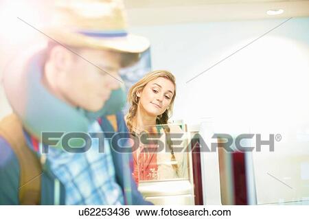 Stock Photograph - Young couple at airport, carrying backpacks, walking through turnstile. Fotosearch