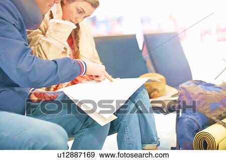 Young couple sitting in airport departure lounge, looking at map, planning trip, mid section View Large Photo Image Stock Photo - Young couple sitting in airport departure lounge, looking at map, planning trip, mid section. Fotosearch