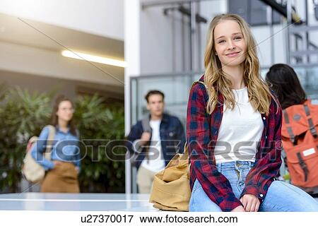 Stock Photo - Young female university student sitting in university lobby, portrait. Fotosearch