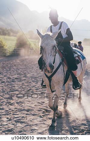 Young hipster man riding horse in sunlit equestrian arena, Primaluna, Trentino-Alto Adige, Italy View Large Photo Image Stock Image - Young hipster man riding horse in sunlit equestrian arena, Primaluna, Trentino-Alto Adige, Italy. Fotosearch