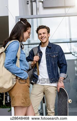 Stock Photo - Young male and female university students laughing together in university lobby. Fotosearch